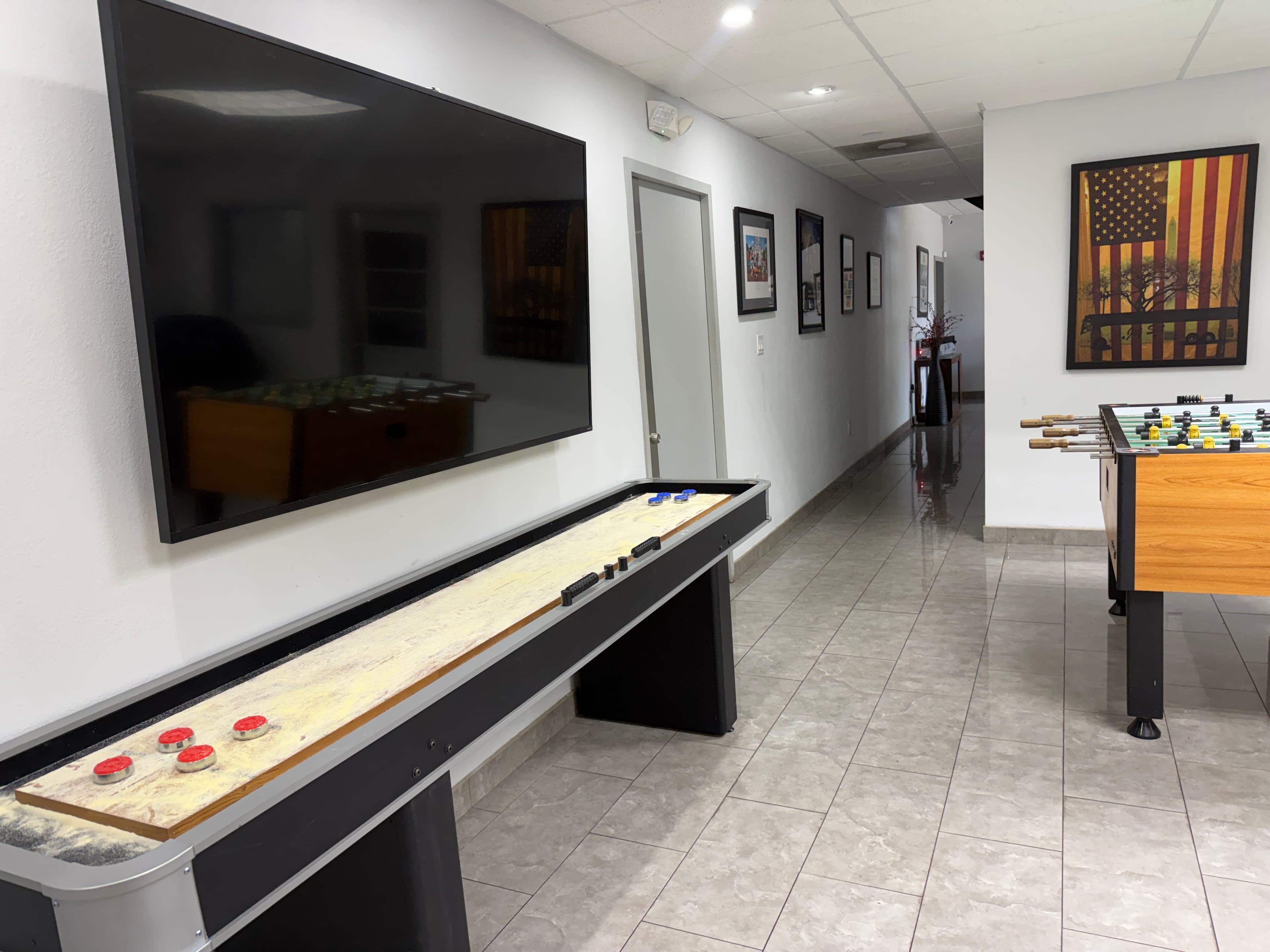 Game room with shuffleboard table, foosball, and large screen TV