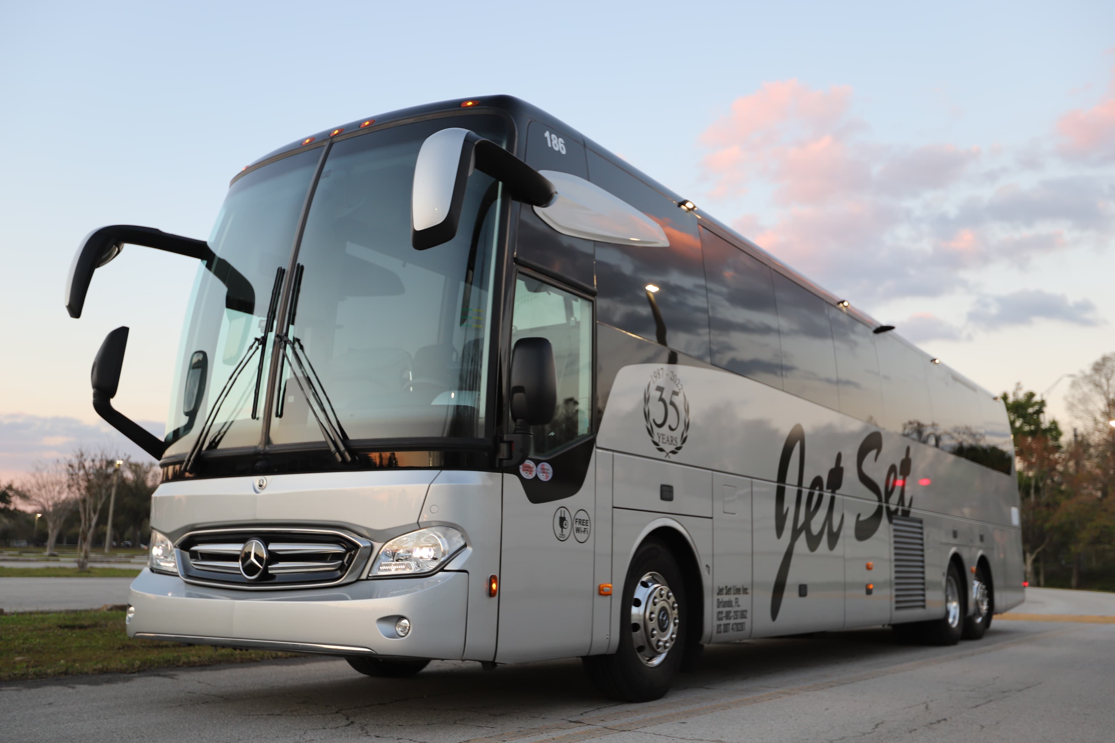 Um ônibus Mercedes-Benz prateado da Jet Set Line estacionado ao entardecer