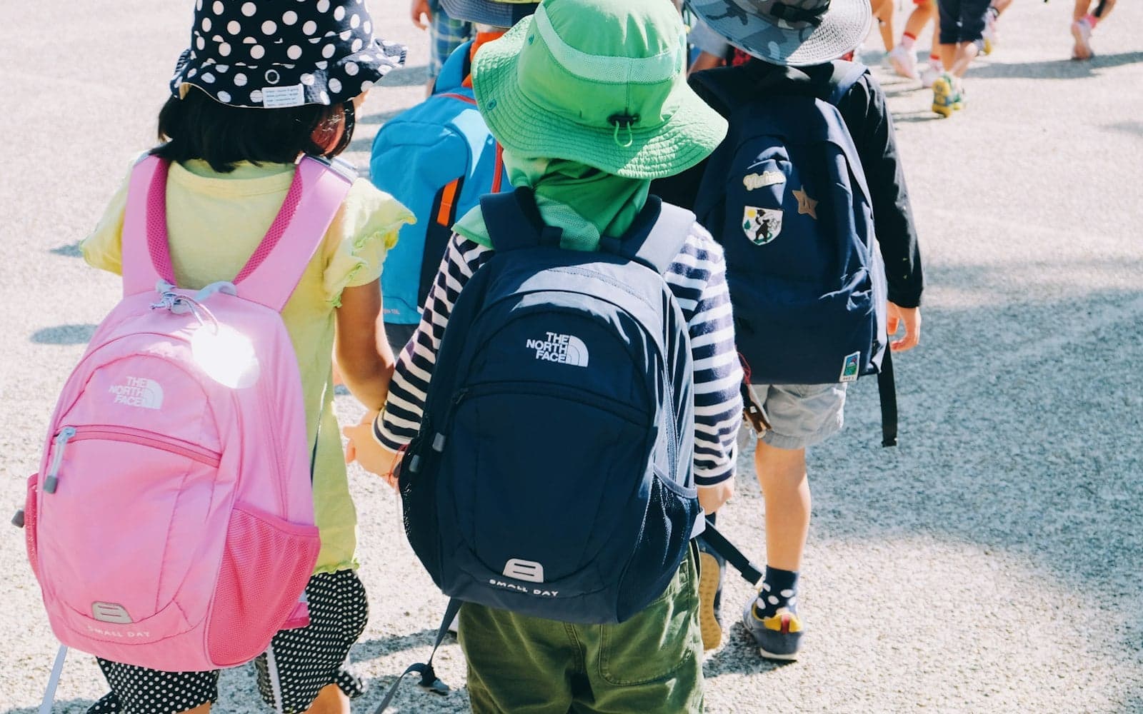 Alunos jovens com mochilas caminhando juntos durante uma excursão escolar