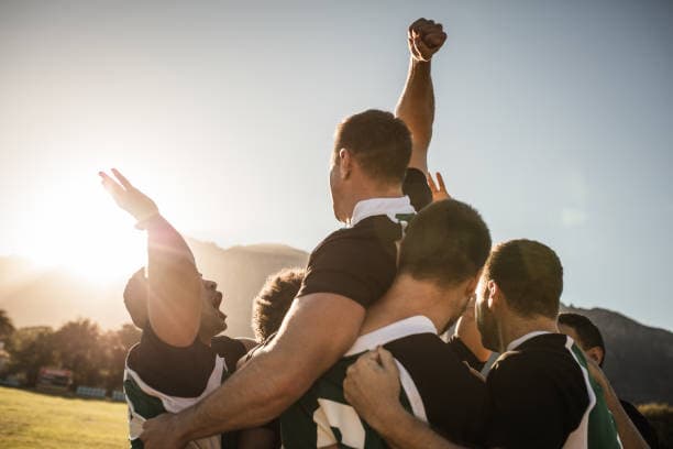 Teammates celebrating together on a sports field at sunset